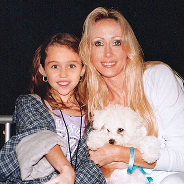 Woman claiming to be Miley Cyrus&rsquo; true birth mother with a young girl and a small white dog in a casual setting