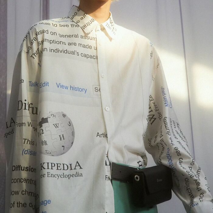 Person wearing a shirt with trippy text and graphics, creating an otherworldly visual effect in bright lighting.