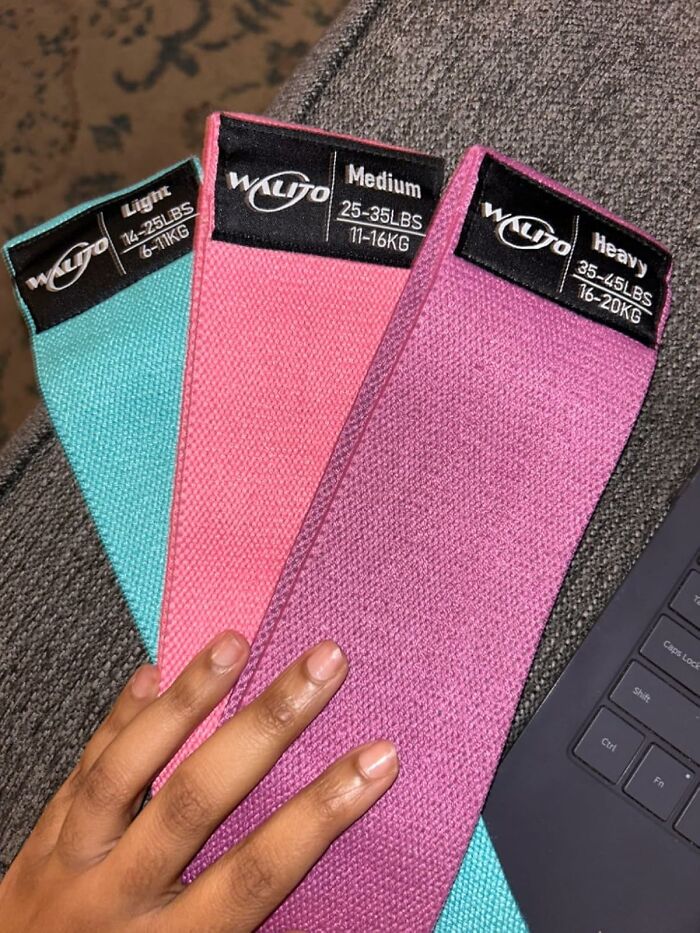 Hand holding light, medium, and heavy resistance bands for apartment friendly fitness workouts at home.