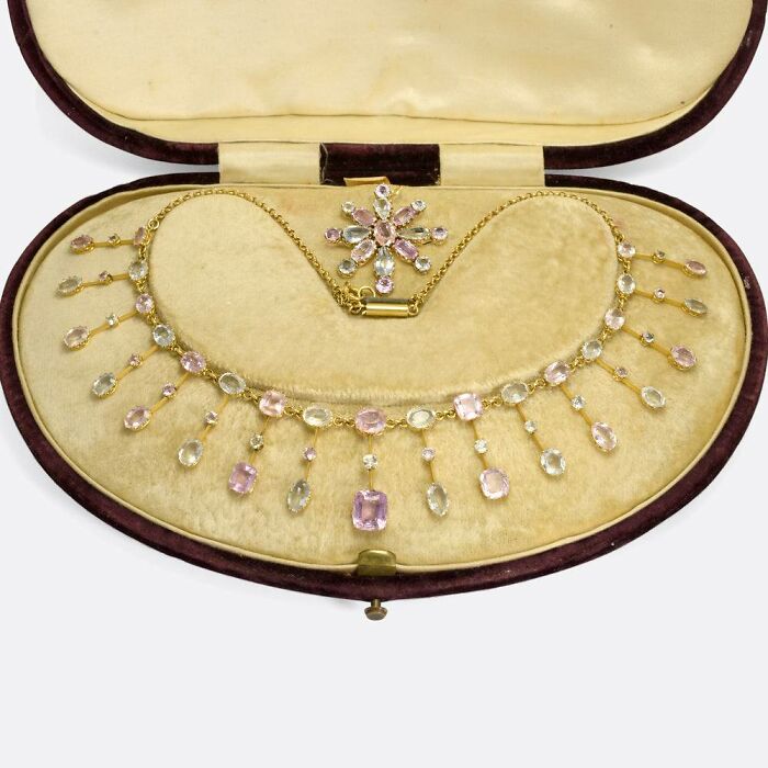 Vintage gold necklace with pastel gemstones displayed in a velvet-lined case, showcasing culture and everyday life from the past.