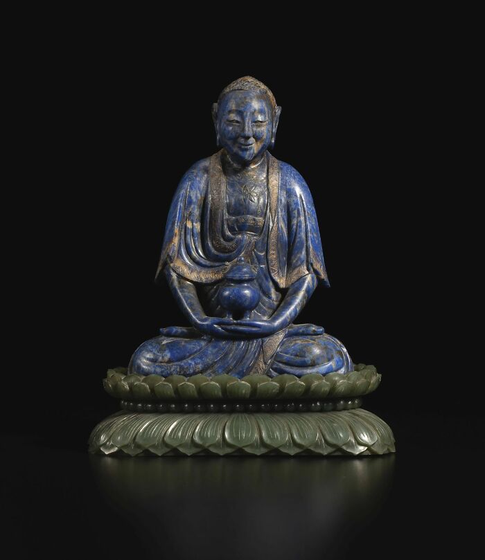 Blue statue of a meditating figure sitting on a carved lotus base, showcasing powerful old photos capturing culture and emotion.