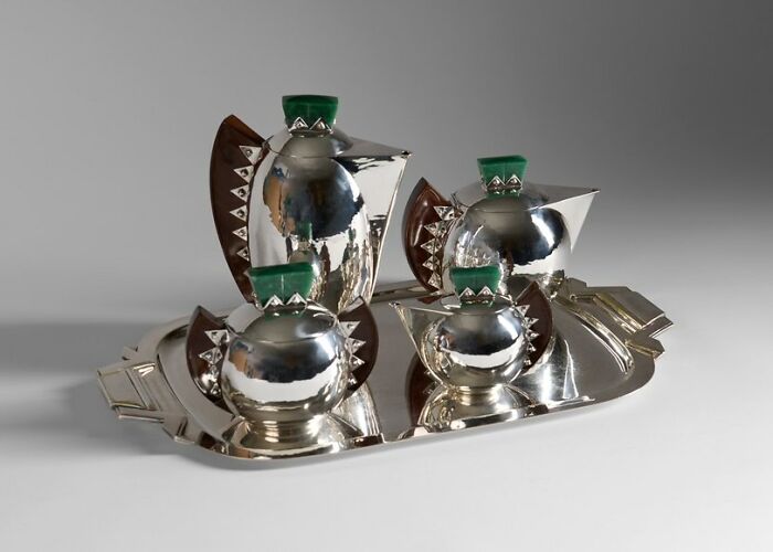 Art Deco silver tea set with geometric design and green accents, reflecting culture and everyday life in the past.