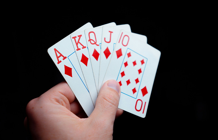 Hand holding a royal flush in diamonds, a classic depiction of the best party game for card players.