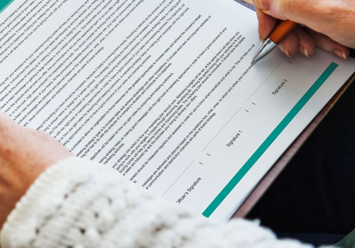 Persona firmando documento oficial sobre escándalos en oficinas que impactaron ambientes laborales y provocaron despidos inmediatos