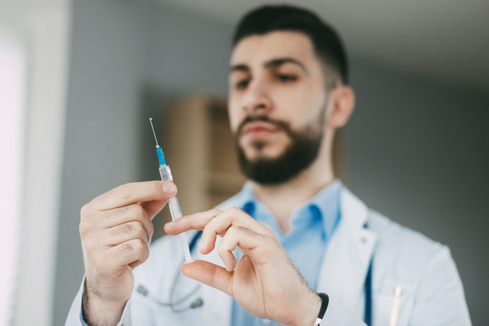 Male doctor preparing a syringe in a clinical setting, illustrating embarrassing moments in front of doctors.