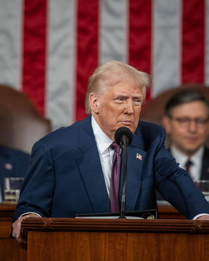 Donald Trump speaking at a podium with American flag backdrop amid controversy over post about Rob Reiner and TDS. Donald Trump speaking at a podium with American flag backdrop amid controversy over post about Rob Reiner and TDS.