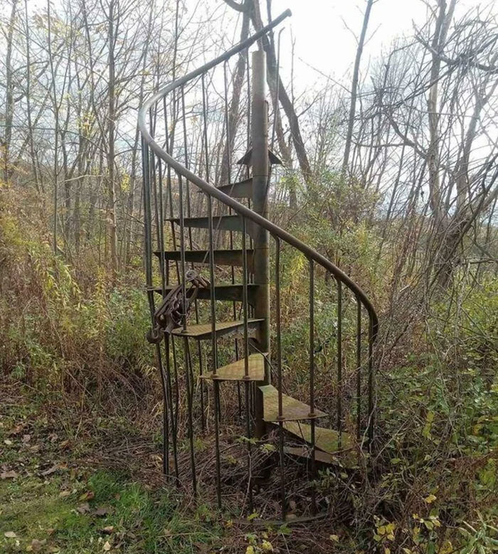 Rusty spiral staircase locked with chains surrounded by dense woods, evoking eerie feelings related to sleeplessness in the woods.