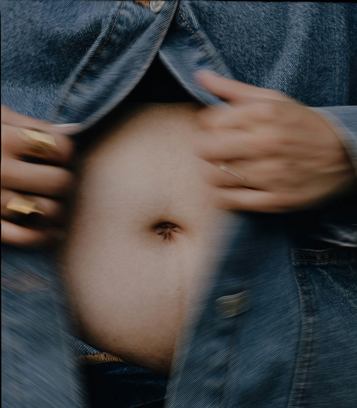 Close-up of a person opening a denim jacket to reveal their belly, highlighting a candid moment related to spicy roasts from kids.