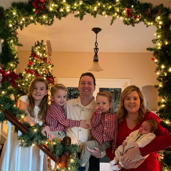 Family celebrating Christmas with festive lights and decorations, featuring the viral Christmas lawyer and children.