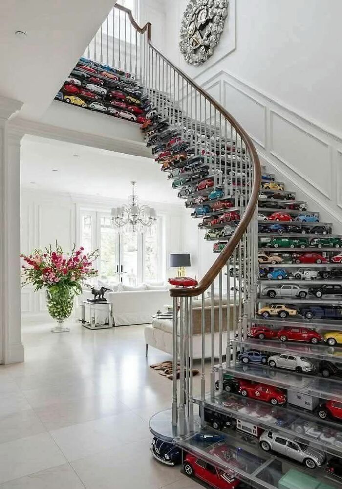 Spiral staircase with clear steps showcasing a collection of colorful model cars, creating a trippy picture effect.