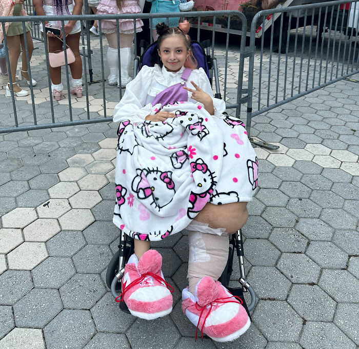 14YO girl with rare condition recovering in wheelchair after 17-hour surgery to remove 174lb leg, wrapped in Hello Kitty blanket