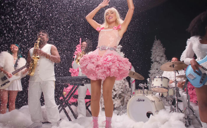 Gwen Stefani performing in a pink outfit amid snowy set, sparking controversy over her Rockefeller Tree Lighting attire.