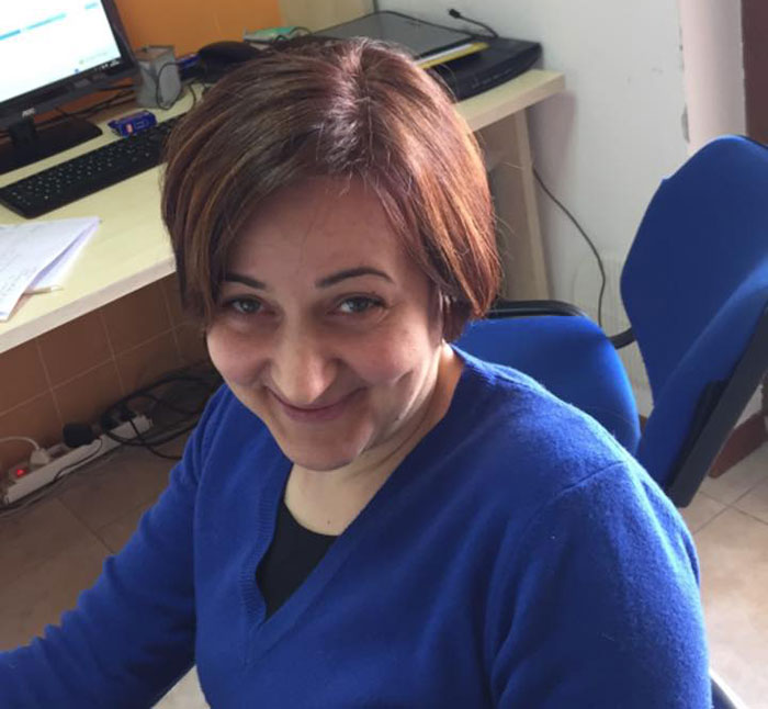 Woman in a blue sweater sitting indoors, representing the town on alert after an Italian mother and daughter&rsquo;s fatal Christmas dinner.