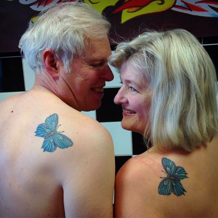 Older couple smiling at each other showing matching blue butterfly tattoos on their upper backs, showcasing wholesome tattoos meaning.