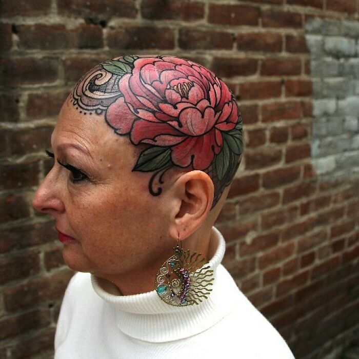 Woman with a large, colorful flower tattoo covering her shaved head, showcasing wholesome tattoos with deep meaning.