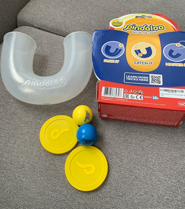 Pindaloo skill game with yellow discs, blue and yellow balls, and packaging as quirky gifts for unhinged taste friends.
