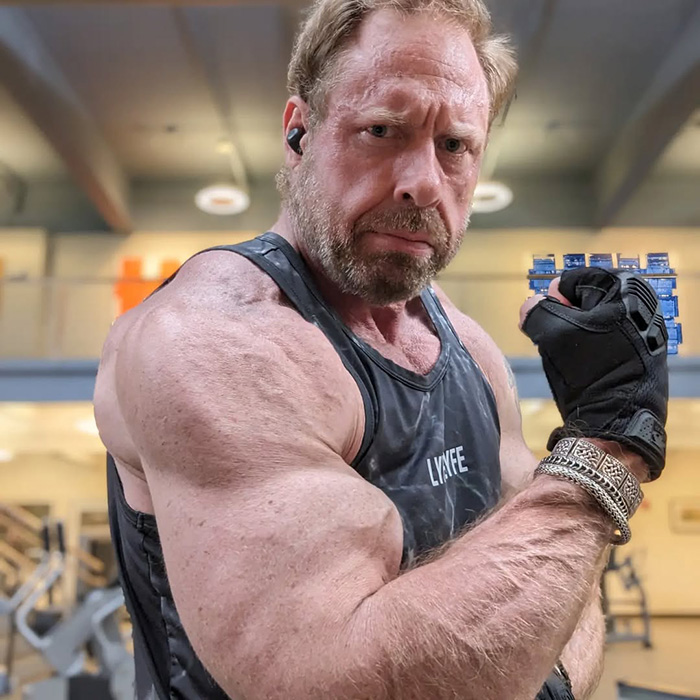 Muscular man in gym flexing bicep wearing black tank top and glove, illustrating scarier than Terminator concept.