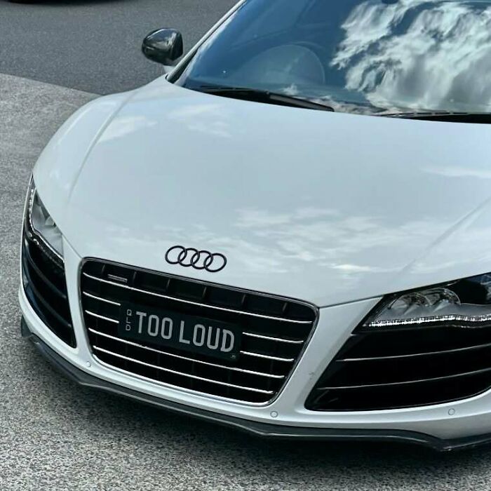 White Audi car with a hilarious personalized license plate reading TOO LOUD, capturing attention and making strangers do double takes.