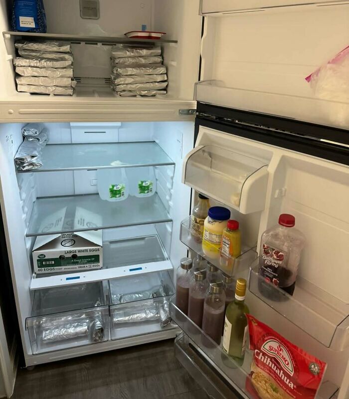Open fridge with organized dude fridge items including wrapped food, eggs, beverages, and condiments on shelves and door compartments.