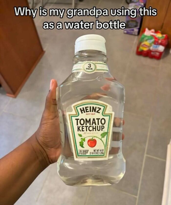 Hand holding a Heinz tomato ketchup bottle filled with water, highlighting a quirky dude fridge item.