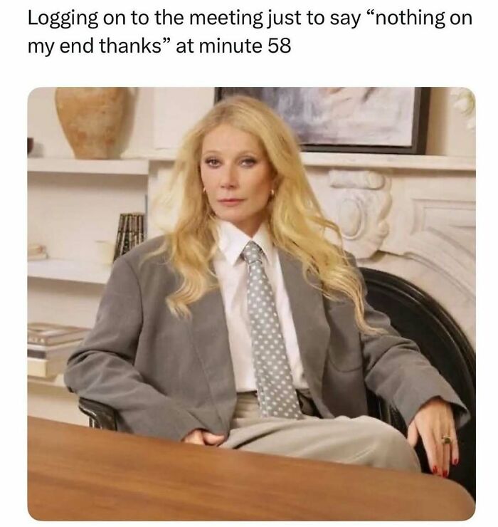 Woman in oversized suit sitting at a desk with a deadpan expression, relatable meme for therapy wait times and humor.
