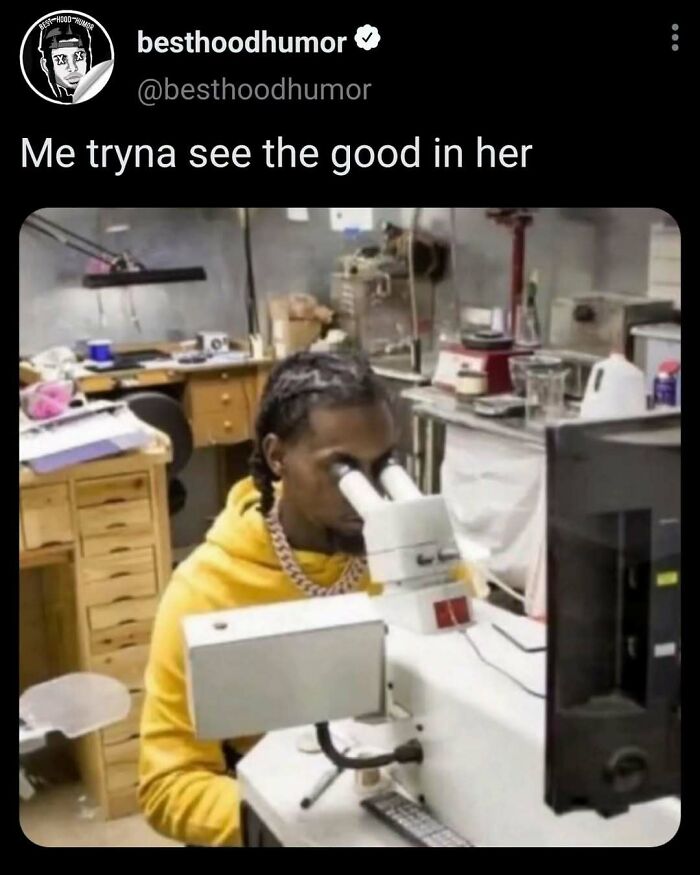 Person in a yellow hoodie looking through a microscope in a cluttered lab, illustrating funny memes concept.