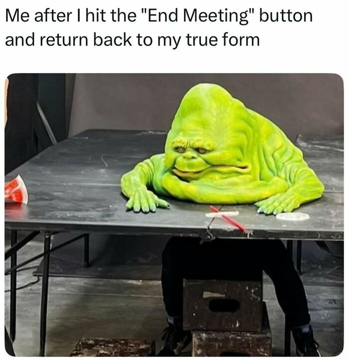 Person wearing a green slime costume sitting at a table, representing a funny meme for therapist waiting scroll humor.