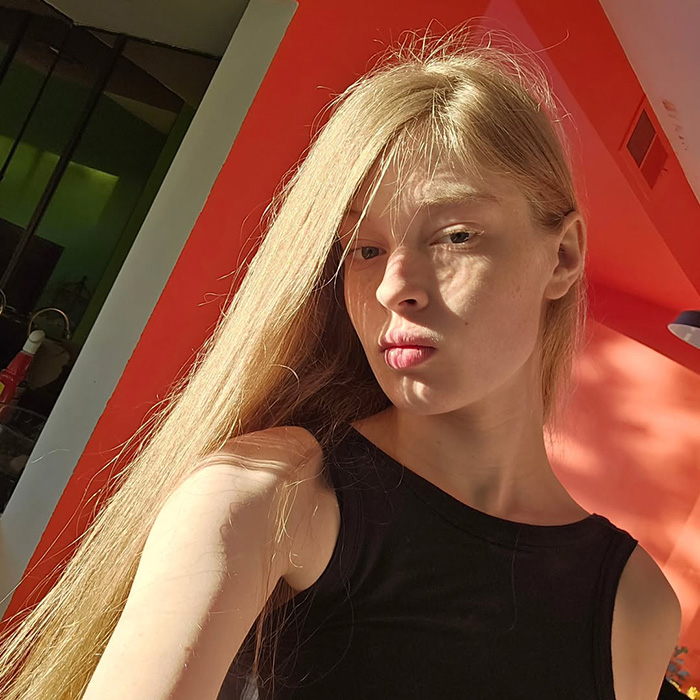 Young woman with long blonde hair in a black sleeveless top, highlighted by sunlight, representing tragic mental illness awareness.