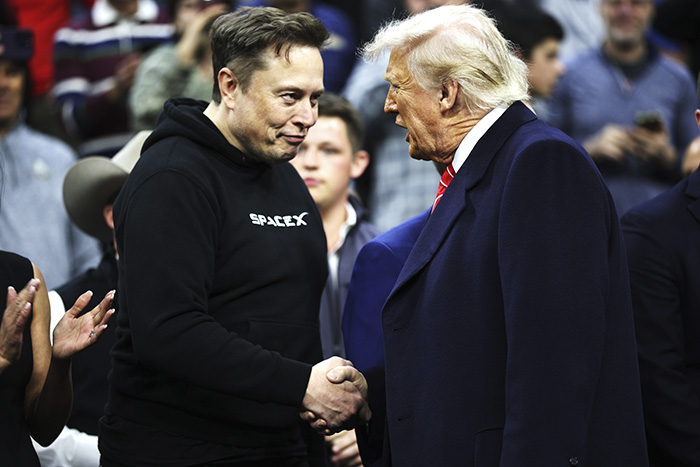 Elon Musk in a black SpaceX hoodie shaking hands with a man in a dark coat amid a crowd, highlighting tragic mental illness discussion.