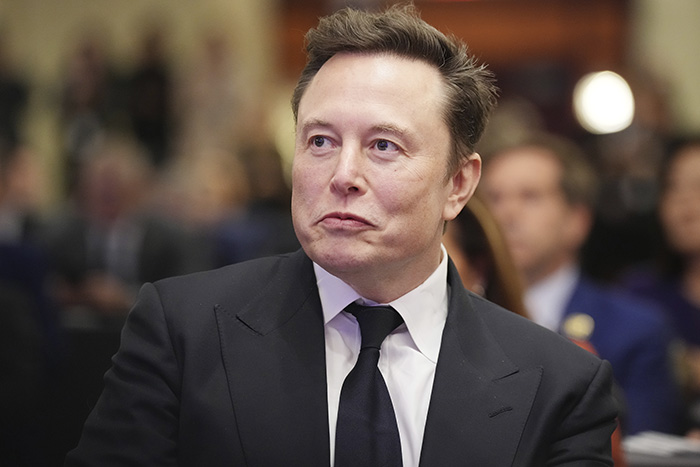 Elon Musk in a black suit and tie at a formal event amid discussions on tragic mental illness and public outrage.