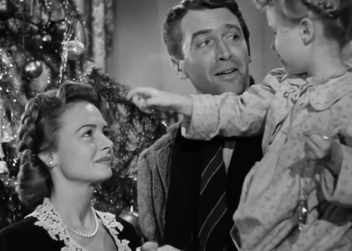 Black and white scene from classic Christmas movie with family by decorated tree, highlighting beloved Christmas classic controversy.