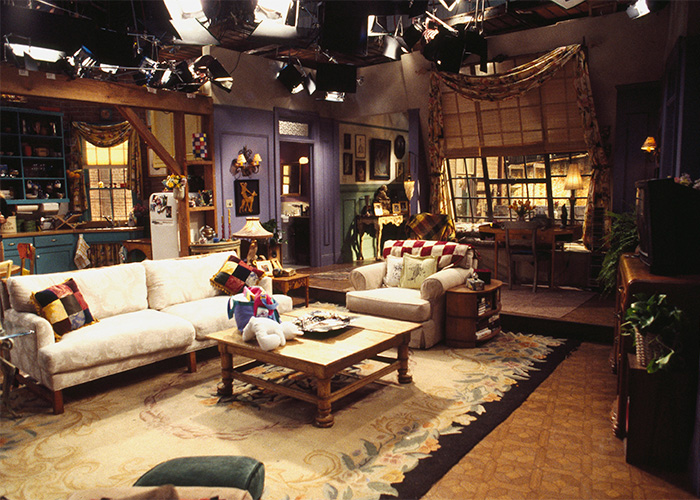 Rarely-seen pop culture shot of a cozy living room set with vintage furniture and warm lighting in a TV show studio.