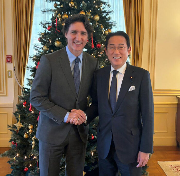 Justin Trudeau and Japan's ex-PM shaking hands in front of a decorated Christmas tree during a formal meeting. Justin Trudeau and Japan's ex-PM shaking hands in front of a decorated Christmas tree during a formal meeting.