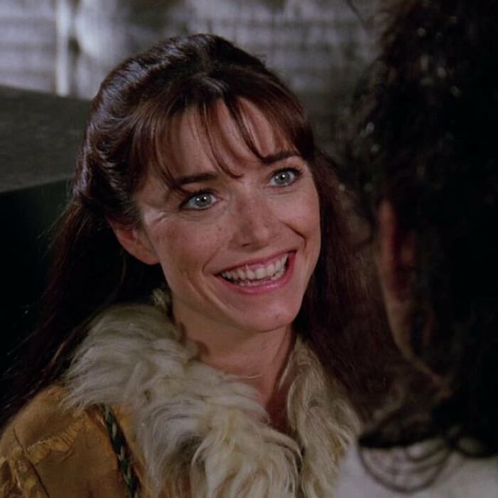 Smiling woman with bangs and fur-collared coat engages in conversation, highlighting Hollywood actresses starting to look identical.
