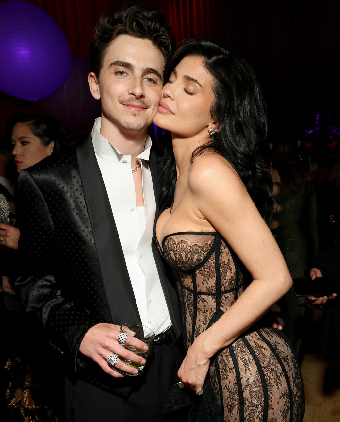 Timoth&eacute;e Chalamet in a black tuxedo and Kylie Jenner in a lace dress posing together at a red carpet event.