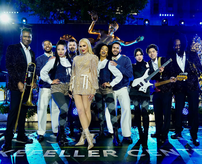 Gwen Stefani wearing a glittery outfit with her band at Rockefeller Center during the tree lighting event.