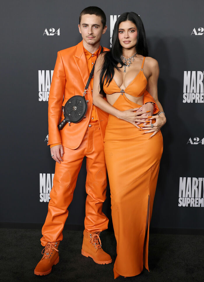 Timoth&eacute;e Chalamet and Kylie Jenner on the red carpet wearing matching orange outfits with a unique fashion detail.