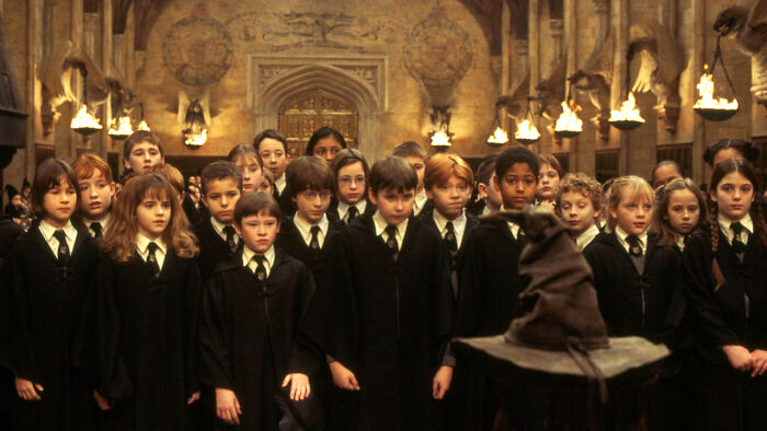Group of young Hogwarts students in robes standing before the sorting hat during the Harry Potter challenge scene.