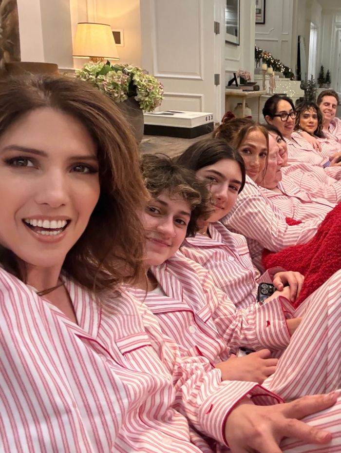 Group of people wearing matching striped pajamas in a Christmas photo with an odd detail sparking Photoshop skills debate.