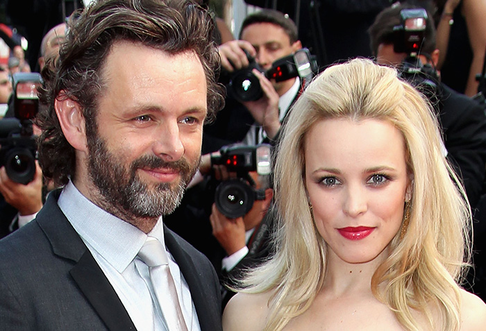 Michael Sheen and a woman at a red carpet event, captured by photographers with cameras in the background.