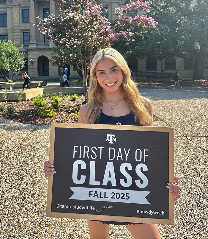 Young woman holding a sign on the first day of class, related to mom of late cheerleader and crucial phone clue case.