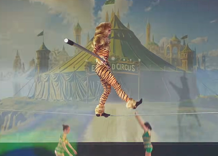 Performer in a tiger costume walking a tightrope during a Wizard of Oz performance amid audience outrage and walkouts.