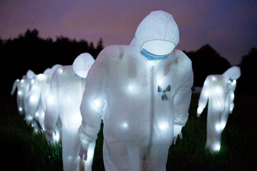People wearing glowing white hazmat suits and masks at night in a dark outdoor setting, illustrating dangerous places to visit.