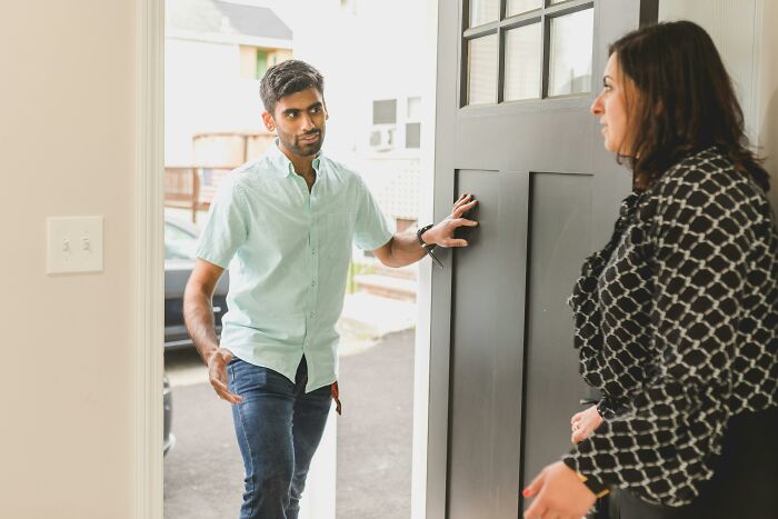 Man entering home holding door open while woman inside watches, illustrating calm or lose it scenarios concept.