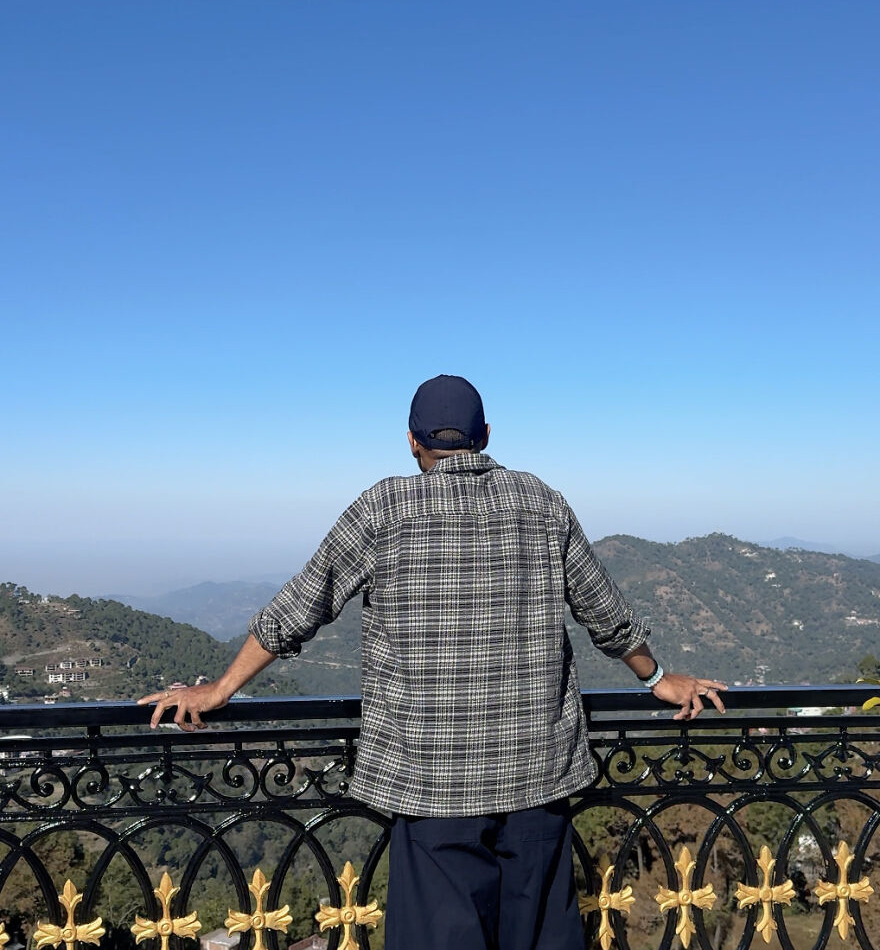 Person overlooking scenic mountain hills in Himachal Pradesh under a clear blue sky, exploring hidden natural gems.