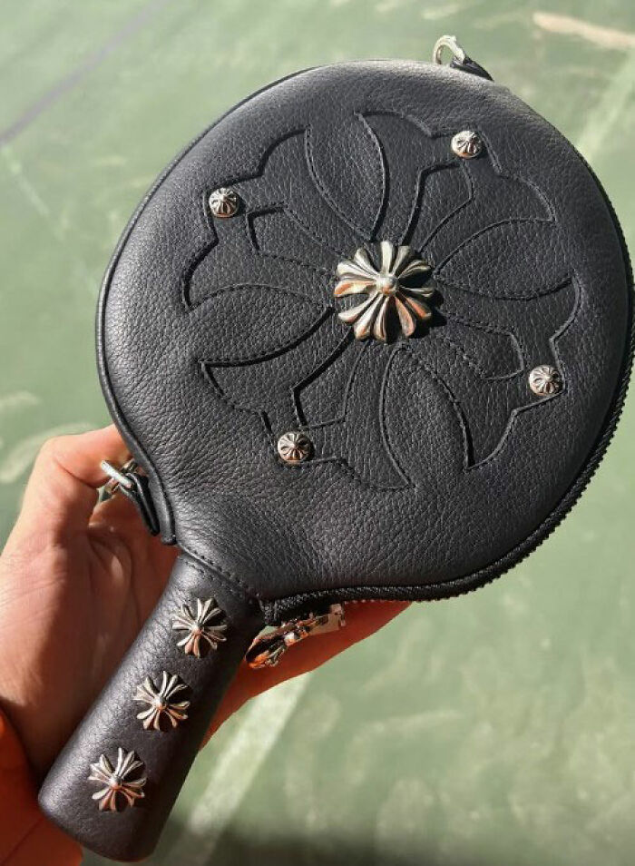 Black leather handbag with metal flower studs in a hand, linked to Timoth&eacute;e Chalamet's red carpet look odd detail