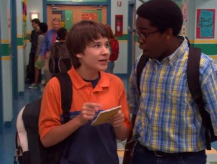 Two young actors in a school hallway discussing a scene related to Tylor Chase&rsquo;s co-star homelessness story.