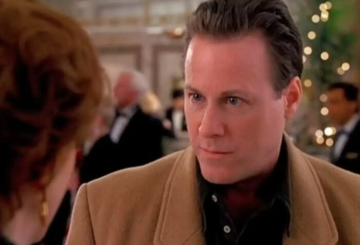 Man in brown coat talking to woman with blurred background capturing a scene related to Kevin&rsquo;s dad&rsquo;s job theory in Home Alone.
