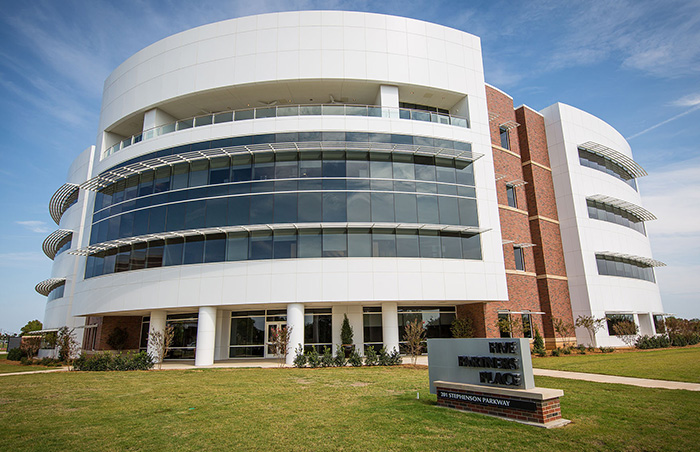 Modern university building with glass windows and a sign, related to student essay exposing trans instructor removal.