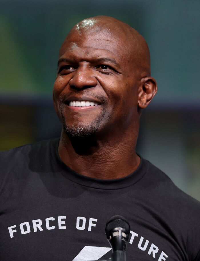 Smiling male celebrity wearing a black shirt speaking at a microphone, representing cancel culture victims and celebrities.